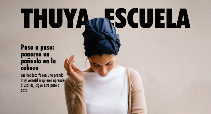 chica de color aparece viendo hacia abajuo con un pañuelo en la cabeza color turquesa, una camiseta blanca básica y un suéter color beige sobre un fondo color crema